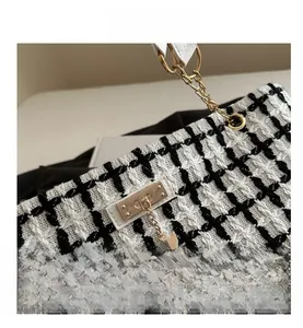 Vue détaillée du tissu en tweed noir et blanc avec charmant pendentif cerf doré sur le sac