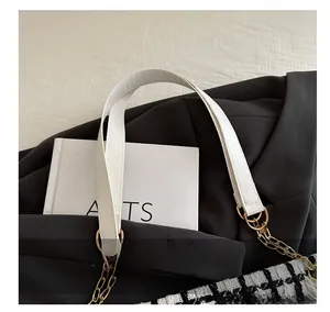 Détail de la poignée en cuir blanc avec chaîne en métal doré sur le sac pied-de-poule