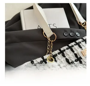 Détail du sac cabas en tweed noir et blanc avec anneaux dorés et bandoulière en cuir blanc