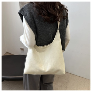 Detail of cream white oversized faux leather tote bag with vertical seam and pleated texture
