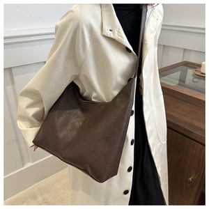 Brown pleated texture faux leather hobo bag worn by model in minimalist room