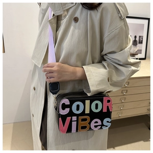 Dettaglio borsa a tracolla in pelle nera con scritta Color Vibes e tracolla viola