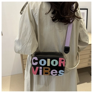 Borsa a tracolla nera alla moda con lettere colorate e tracolla lavanda indossata dalla modella