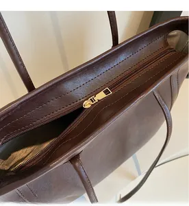 Detail of smooth gold metal zipper closure on a dark brown leather tote bag