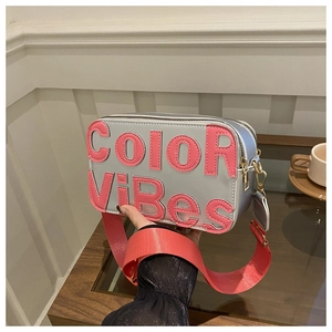 Dettaglio borsa fotografica argento con scritte Color Vibes rosa e tracolla larga
