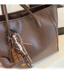 Close-up of brown leather tote bag with decorative chocolate and horse charms