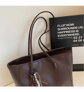 Close-up of deep brown tote bag with woven tassel charm and textured leather detail