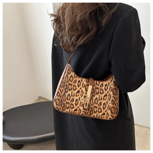 Détail du sac baguette imprimé léopard avec fermoir doré et bordure en cuir portée à l'épaule