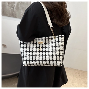 Détail du sac cabas en tweed à carreaux avec chaîne dorée et pendentif cerf à l'épaule
