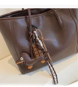 Detail of cute dachshund pendant with chocolate charm on a vintage brown tote bag