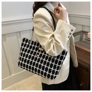 Detail of black and white plaid tweed tote bag with gold deer charm and leather strap