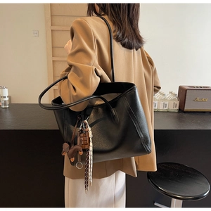 Retro black faux leather tote bag with decorative charms shown on model's shoulder