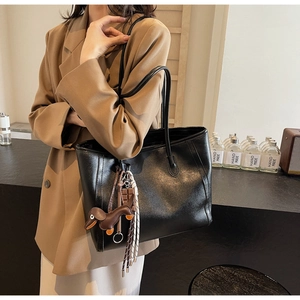 Detail of black tote bag with brown dachshund dog charm and tassel decoration