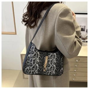 Détail du sac léopard avec fermoir doré porté sous le bras par un mannequin