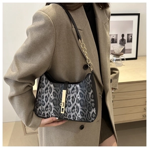 Détail du sac léopard avec fermoir doré et bandoulière en chaîne porté par un modèle
