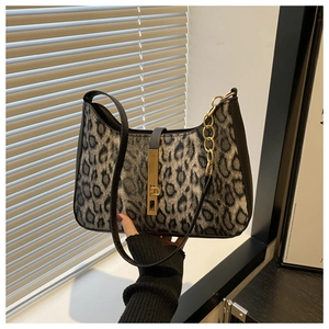 Détail d'un sac sous le bras à motif léopard avec boucle dorée et finitions en cuir noir