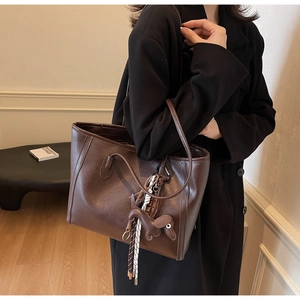Detailed view of deep brown leather tote bag with a small dachshund dog charm hanging