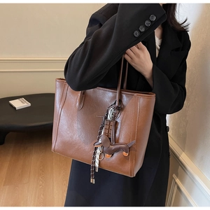 Detail of vintage brown leather tote bag with unique dachshund and chocolate charms