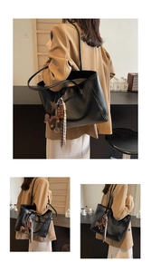 Detail of black leather tote bag with decorative horse charm and woven strap accents