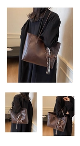 Close-up of a dark brown leather tote bag featuring a creative horse charm and fine stitching