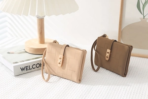 Detail of quilted PU leather wallets with gold metal buckle and wrist strap in warm white