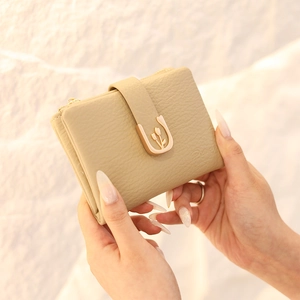 Close-up of khaki pebbled leather wallet with golden tulip buckle held in hands