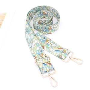 Detail of adjustable floral woven bag strap with golden hardware and lobster clasps