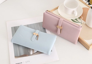 Detail of long PU leather wallets with golden puzzle buckles in blue and purple colors
