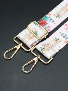 Detail of Christmas themed bag strap with golden hardware and Merry Christmas print