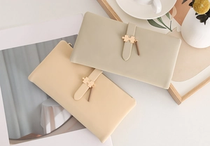 Flat lay of elegant long PU leather wallets with gold pendants and lifestyle accessories