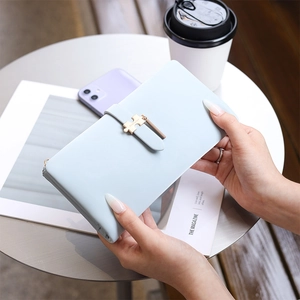 Close-up of light blue long leather wallet with gold puzzle piece charm on a table