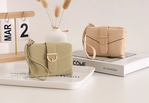 Detail of V-quilted faux leather short wallet with metal buckle and wrist strap
