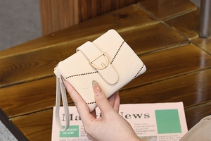 Detail of beige quilted short wallet with gold D-ring buckle on a wooden background
