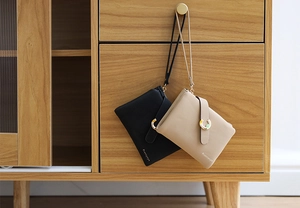 Detail of faux leather wristlet wallets in black and beige with metallic buckles