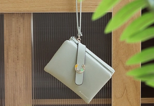 Close-up of mint green leather wallet with gold horseshoe buckle and brand logo