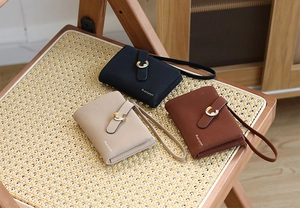 Three short leather wallets with snap closure, gold C logo, and wrist strap detail