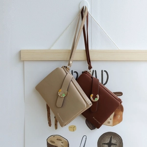 Detail of zip clutch with wrist strap, textured leather, and golden horseshoe buckle