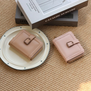 Detail of mini PU leather wallets in light coffee and pink with decorative buckles