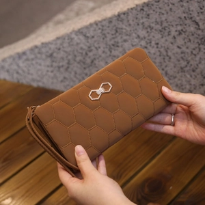 Detail of caramel brown long wallet featuring hexagonal quilting and metal bow clasp