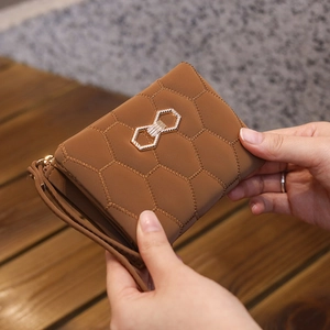 Gros plan d'un porte-monnaie marron matelassé avec boucle nœud dorée et dragonne