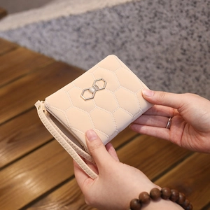 Vue détaillée du portefeuille en cuir PU matelassé beige avec nœud doré et dragonne