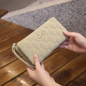 Close-up of beige quilted long wallet with honeycomb stitching and gold hexagon buckle