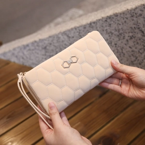Close-up of beige quilted wallet featuring honeycomb pattern and golden bow buckle
