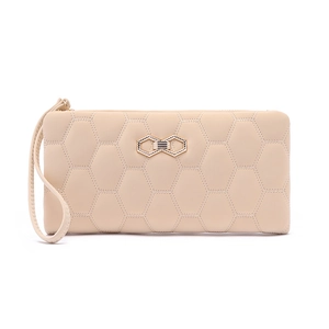 Detail of beige quilted wristlet wallet featuring hexagonal patterns and gold bow clasp