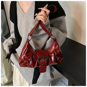 Close-up of shiny dark red leather baguette bag with metal buckle and pleat texture