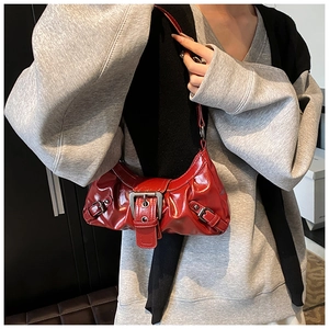 Detail of red glossy leather shoulder bag with vintage silver buckles and ruched design
