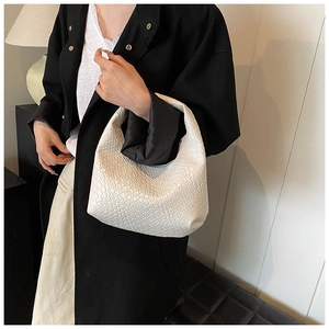 Detail of white woven hobo bag with checkered texture shown on model for shoulder wear