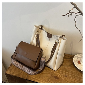 Minimalist beige tote bag and brown crossbody bag with ethnic woven strap on wood