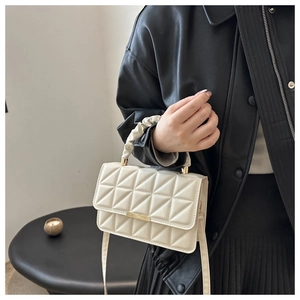Detail of cream quilted square crossbody bag with gold buckle and ruched handle
