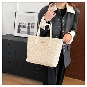 Détail du sac cabas crème avec motif M marron et plaque logo en métal doré chic